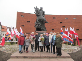 Grupa uczestników heppeningu u stóp pomnika monarchy